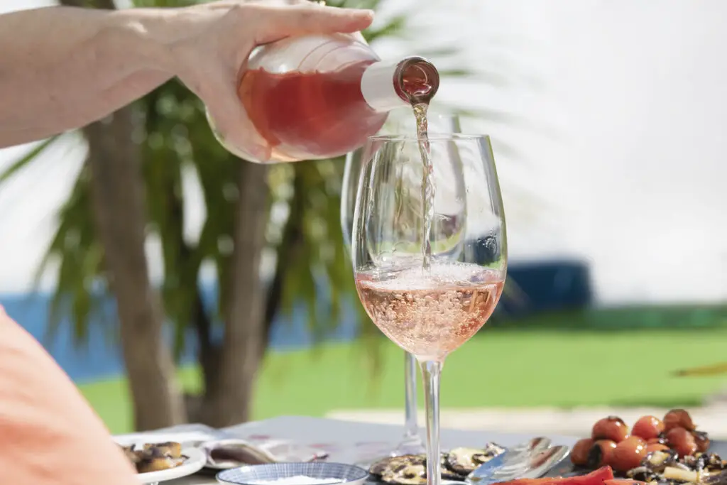 a hand of woman pouring delicious rose wine