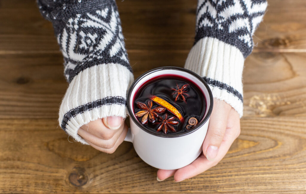 A mug of hot red mulled wine in woman hands