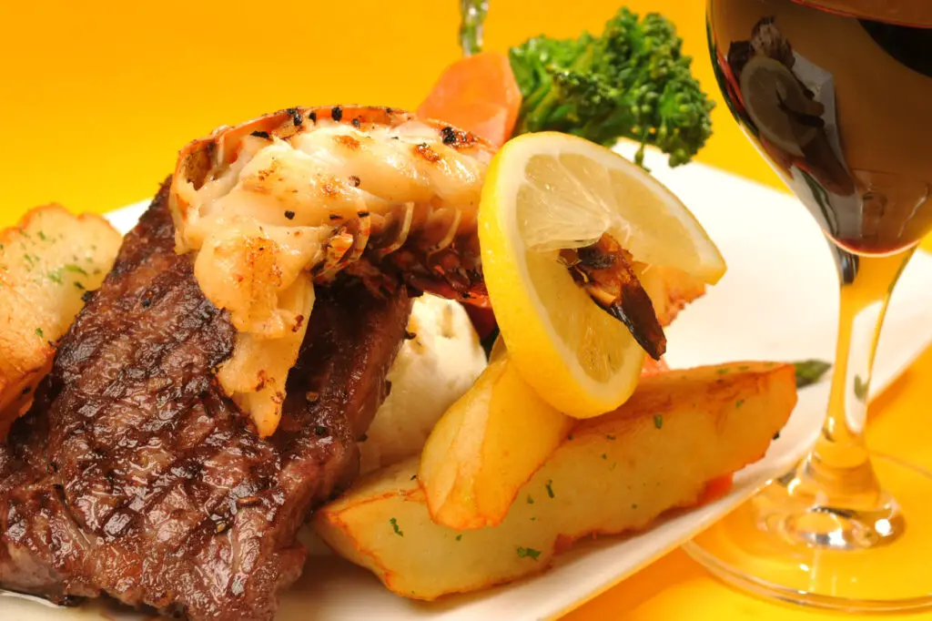 Lobster tail on a new york steak with red wine