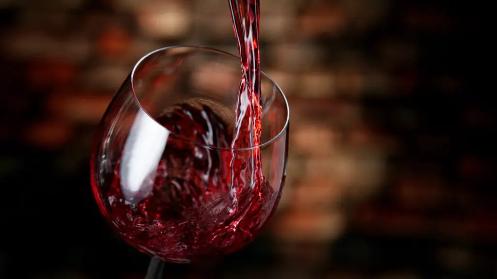 Freeze motion of red wine pouring into glass.