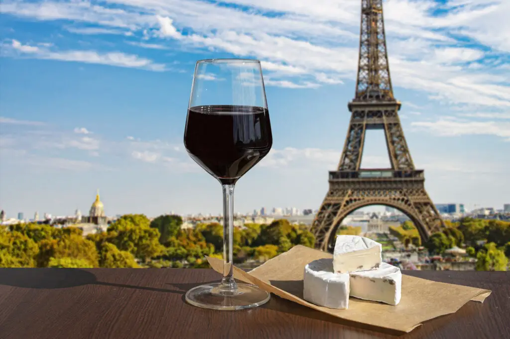Glass of wine with brie cheese on Eiffel tower and Paris skyline background