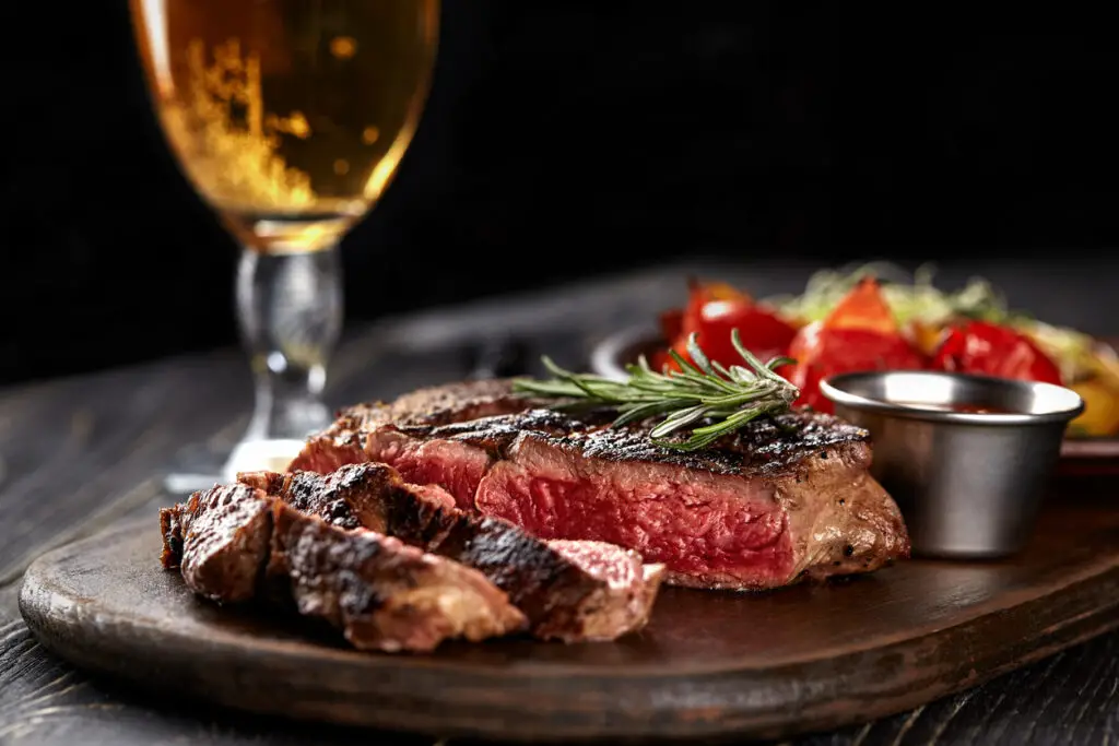 Juicy steak medium rare beef with spices on wooden board on table