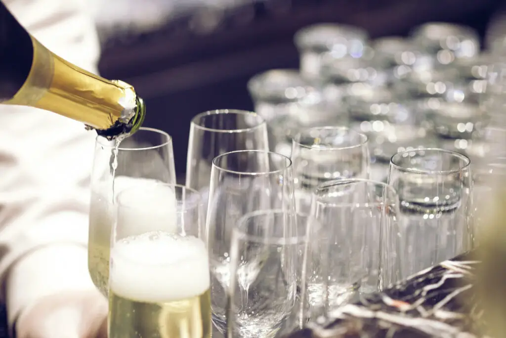 pouring wine in many glasses for dinner party, shot with narrow focus.