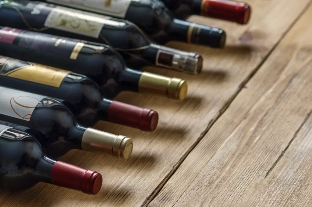 Row of red dry wine bottles on wooden background