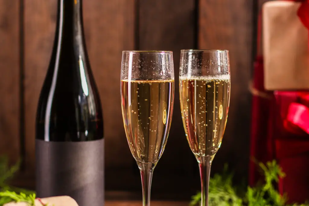 Champagne and new year or christmas (champagne glass, sparkling wine and gifts on the table) menu concept