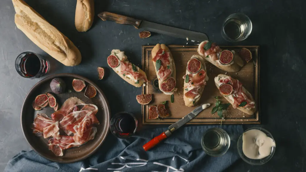 Spanish snacks and wine on a dark concrete background. tapas, pinchos, bruschetta of Delicious ham, jamon, baguette, figs, cheese and herbs on the dining table.