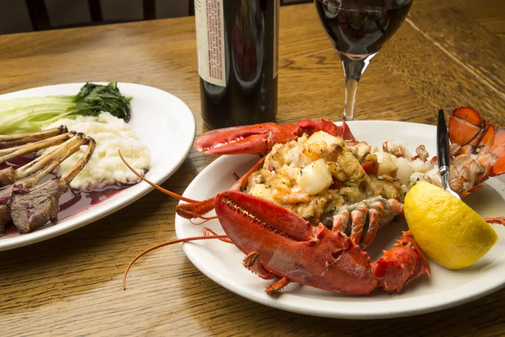 A closely cropped shot of delicious lobster and lamb served with red wine