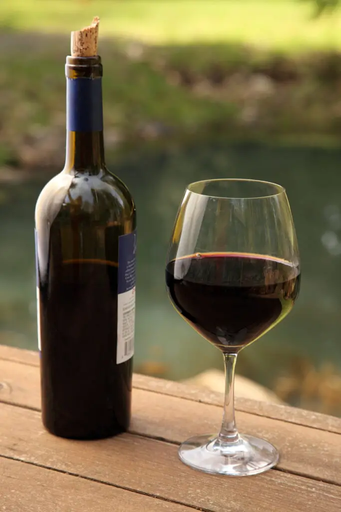 Bottle and glass of red wine outdoors