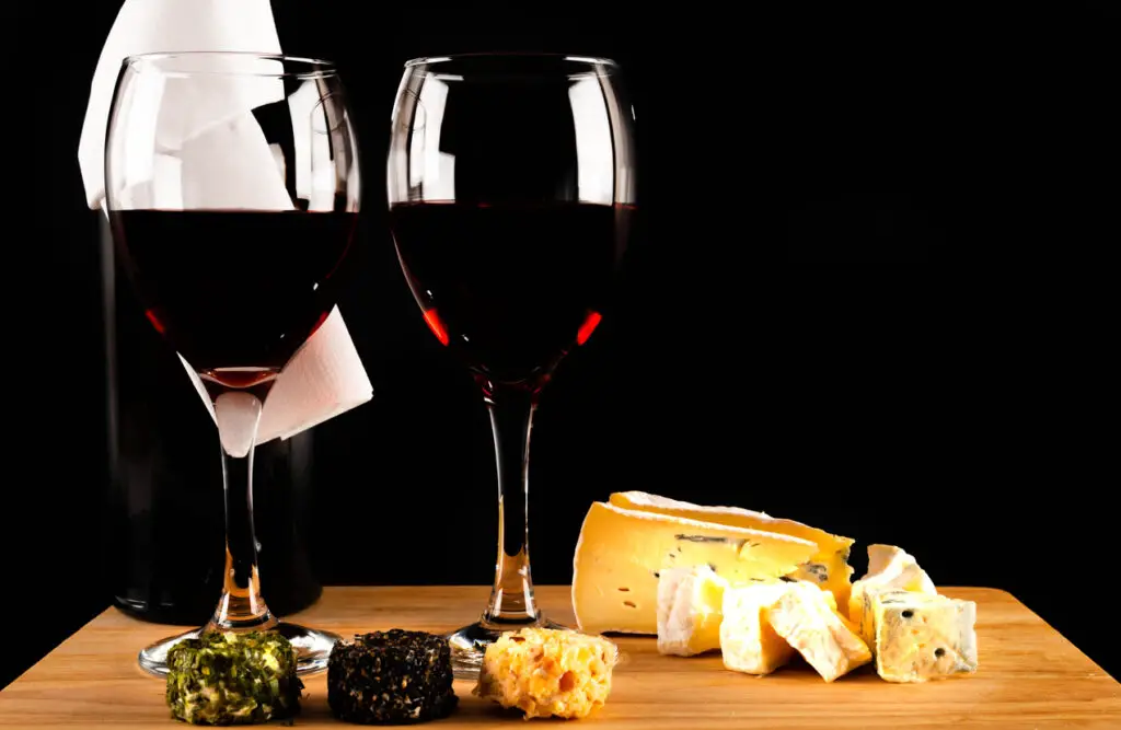 Red wine and set of different cheeses on a wooden board, delicious snack