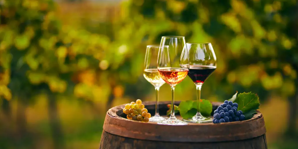 Three glasses of white, rose and red wine on a wooden barrel