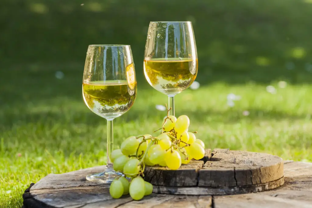 white wine with grapes on old wooden table