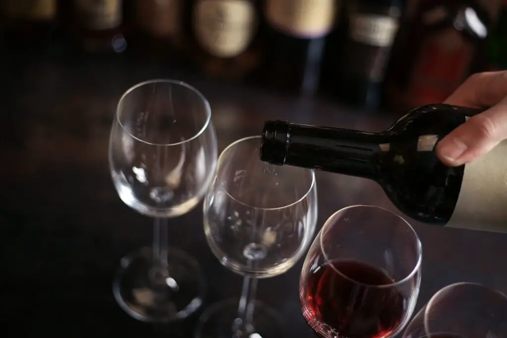 bartender pours a glass of red wine