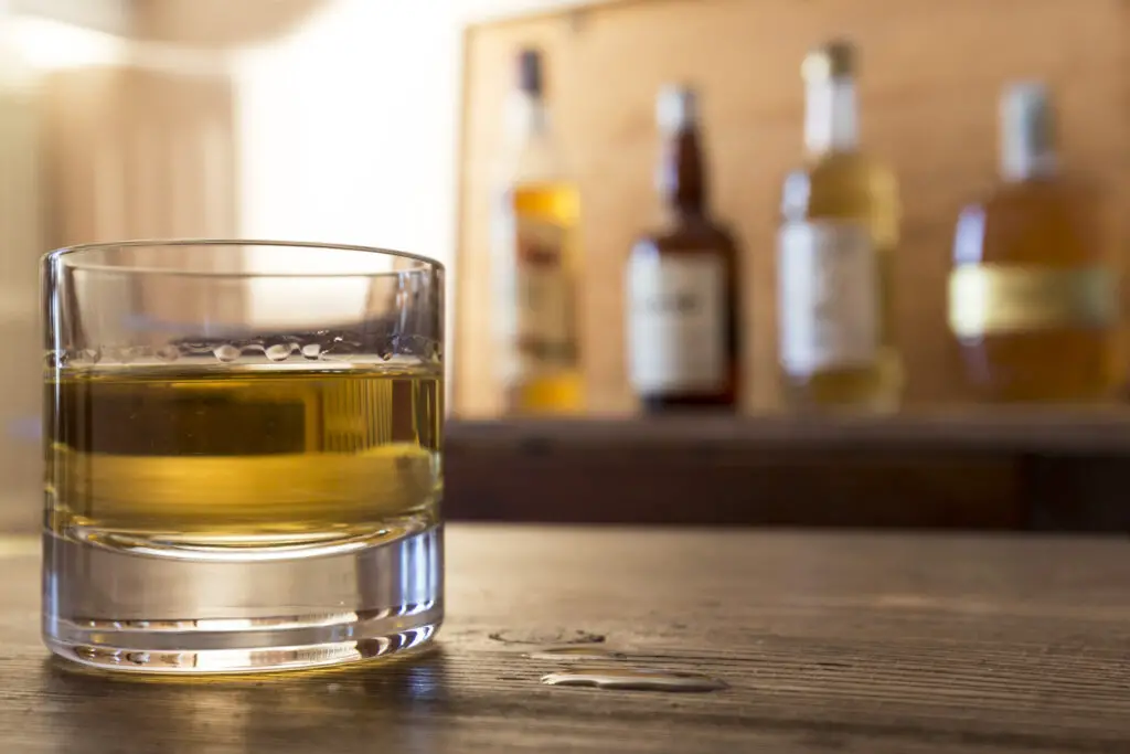 glass with whisky on wooden table