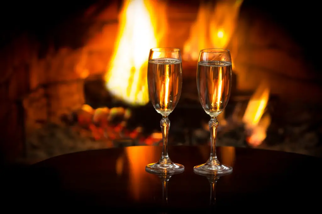 Sparkling wine in front of warm fireplace. Romantic, cozy atmosphere