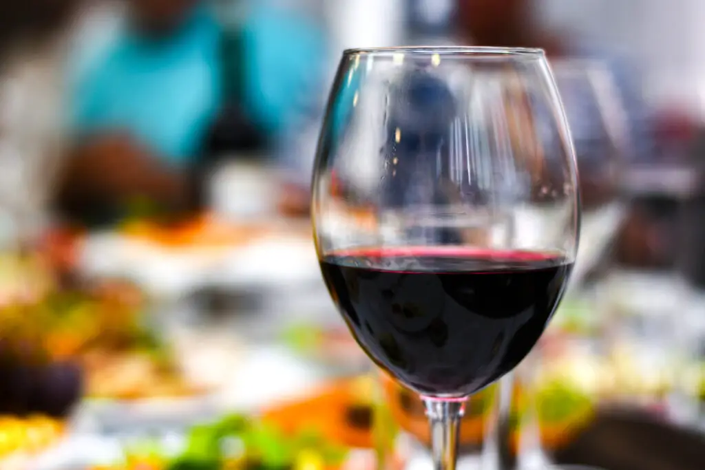 A glass of red wine stands on a festive table