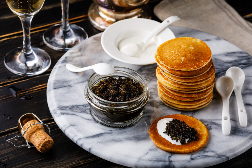 Black Caviar, Mini Pancakes and Sour Cream Holiday Party Appetizer on dark background