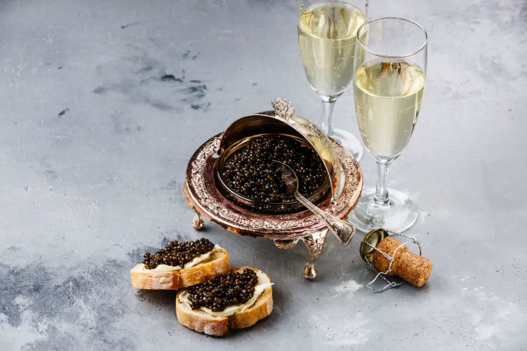 Black caviar in silver bowl, sandwiches and champagne