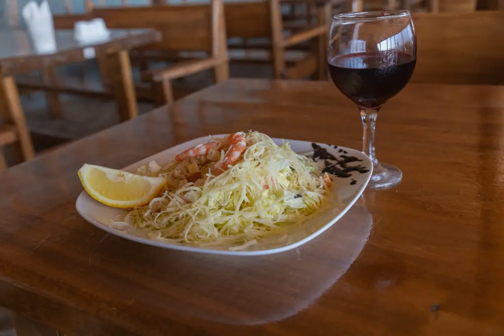 Caesar salad with shrimp and a glass of wine.