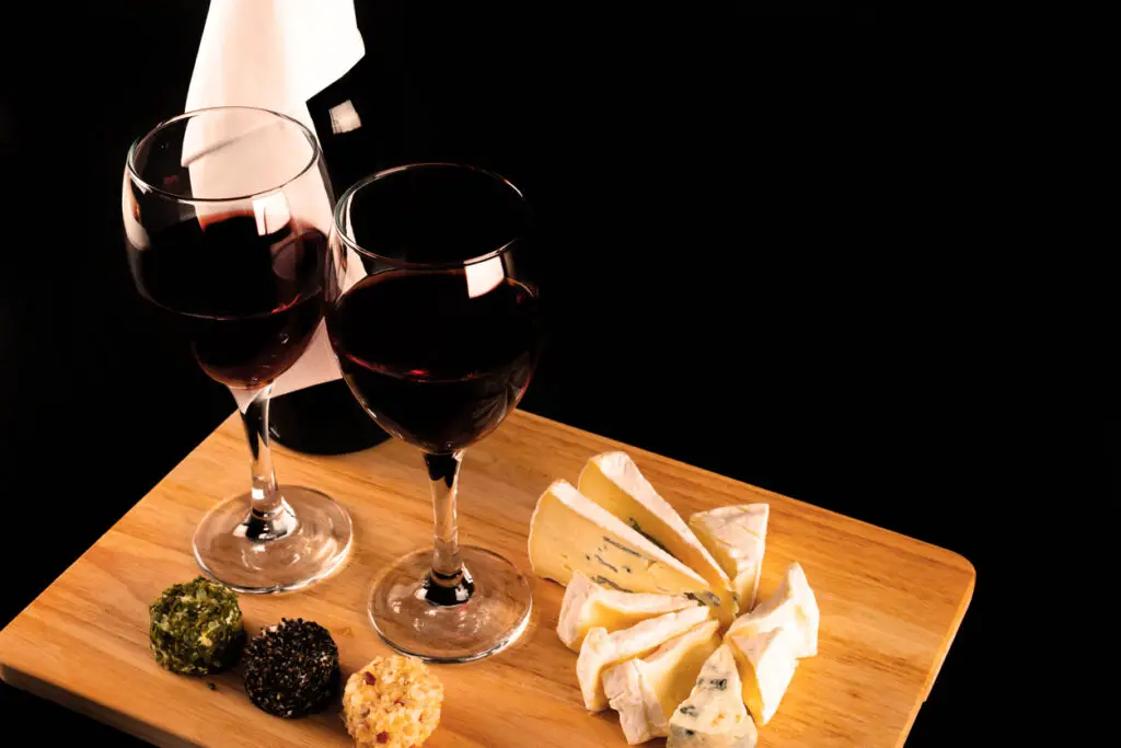 Red wine and set of different cheeses on a wooden board, delicious snack
